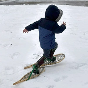 child in winter coat and snowshoes